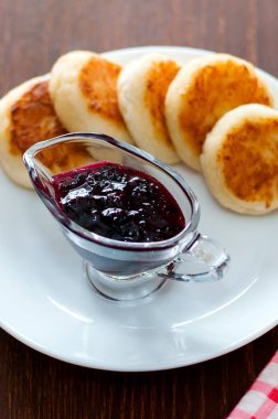 Kuş üzümü reçeli ile Peynir krep, bir çatal, bir çay kaşığı ve peçete, yatay formatile beyaz bir tabak üzerinde