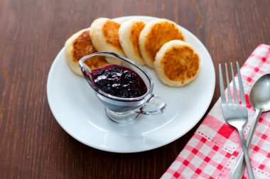 Kuş üzümü reçeli ile Peynir krep, bir çatal, bir çay kaşığı ve peçete ile beyaz bir tabak üzerinde, üstten görünümü.