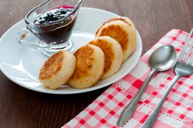 Reçelli peynirli krepler, çatal, çay kaşığı ve peçete ile beyaz bir tabakta, yatay formatta