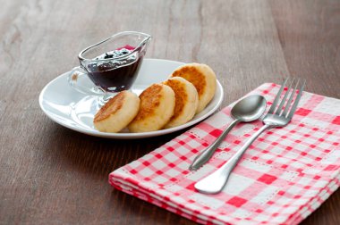 Reçelli peynirli krepler, çatal, çay kaşığı ve peçete ile beyaz bir tabakta, yatay formatta