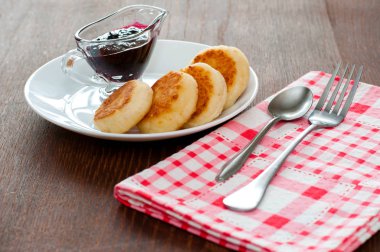 Reçelli peynirli krepler, çatal, çay kaşığı ve peçete ile beyaz bir tabakta, yatay formatta, yan görünüm