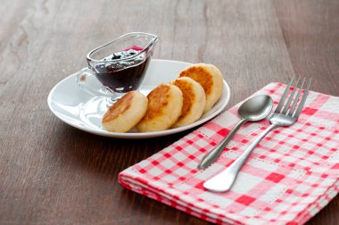 Reçelli peynirli krepler, çatal, çay kaşığı ve peçete ile beyaz bir tabakta, yatay formatta, yan görünüm