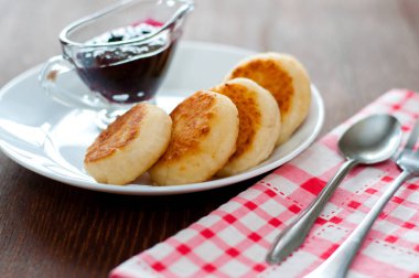 Reçelli peynirli krep, beyaz tabakta, çay kaşığı, çatal ve mutfak havlusu ile