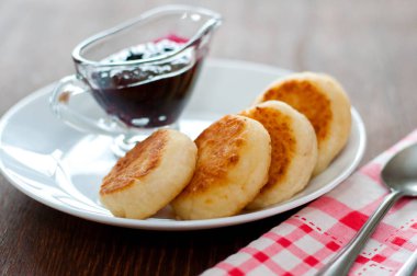 Reçelli peynirli krep, beyaz tabakta, çay kaşığı, çatal ve mutfak havlusu ile