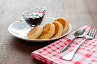 Reçelli peynirli krep, beyaz bir tabaktabak, çay kaşığı, çatal ve mutfak havlusu, yan görünüm