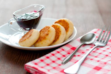 Reçelli peynirli krep, beyaz bir tabaktabak, çay kaşığı, çatal ve mutfak havlusu, yan görünüm