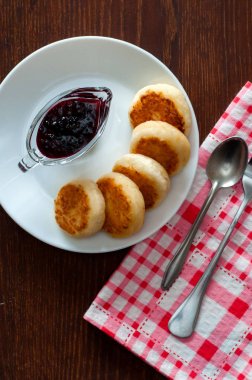 Reçelli peynirli krep, beyaz bir tabakta, bir çay kaşığı, çatal ve mutfak havlusu, üstten görünüm, dikey fotoğraf