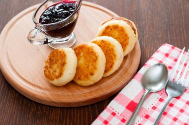 Reçelli peynirli krepler, ahşap bir platformda, bir çay kaşığı, çatal ve mutfak havlusu ile, üstten görünümü,