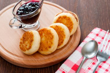 Reçelli peynirli krepler, ahşap bir platformda, bir çay kaşığı, çatal ve mutfak havlusu ile, üstten görünümü,