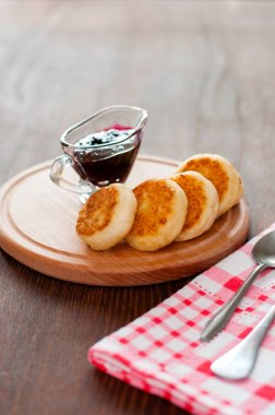 Kuş üzümü reçeli ile Peynir krep, tahta bir tahta üzerinde, bir çatal, kaşık ve bulaşık bezi ile, dikey biçimli