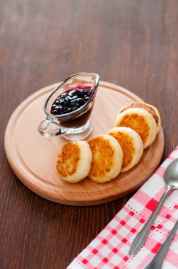 Kuş üzümü reçeli ile Peynir krep, ahşap bir platform üzerinde, bir çatal, kaşık ve mutfak havlusu, dikey format