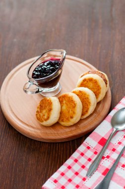 Kuş üzümü reçeli ile Peynir krep, ahşap bir platform üzerinde, bir çatal, kaşık ve mutfak havlusu, dikey format