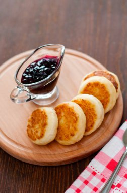 Kuş üzümü reçeli ile Peynir krep, ahşap bir platform üzerinde, bir çatal, kaşık ve mutfak havlusu, dikey format