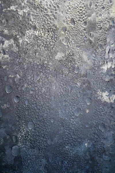 Vinterbakgrund, frusna regndroppar på glaset från stark frost och vind, konsistensen av is på fönstret. — Stockfoto