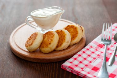 Ahşap bir tahta üzerinde ekşi krema ile Peynir krep, bir çatal ve peçete yatay formatında.