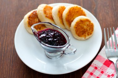 Kuş üzümü reçeli ile Peynir krep, bir çatal, bir çay kaşığı ve peçete ile beyaz bir tabak üzerinde, üstten görünümü.