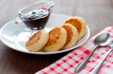 Reçelli peynirli krep, beyaz tabakta, çay kaşığı, çatal ve mutfak havlusu ile