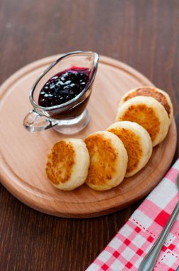 Kuş üzümü reçeli ile Peynir krep, ahşap bir platform üzerinde, bir çatal, kaşık ve mutfak havlusu, dikey format