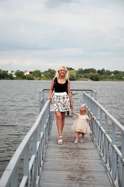 Anne ve kızı yürüyor, eğleniyor, nehrin kıyısında oynuyorlar. Tfamily ilişkileri, annelik kavramı .