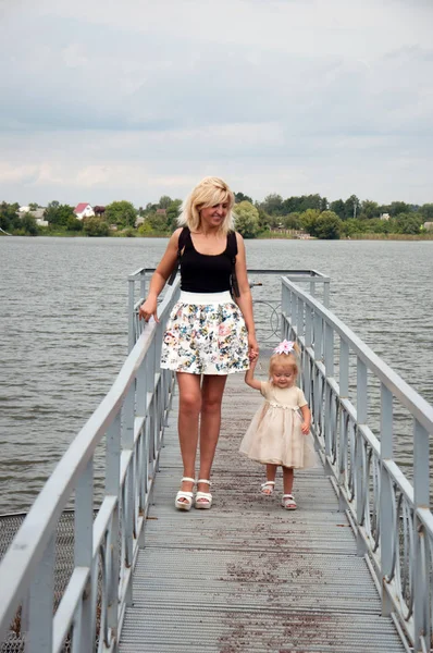 Anne ve kızı yürüyor, eğleniyor, nehrin kıyısında oynuyorlar. Tfamily ilişkileri, annelik kavramı .