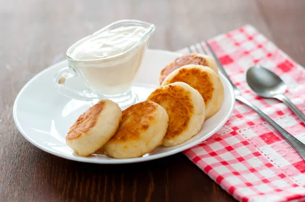 Bir çatal, bir çay kaşığı ile beyaz bir tabak üzerinde ekşi krema ile Peynir krep . Menü tasarımı, mutfak siteleri için kullanılabilir.