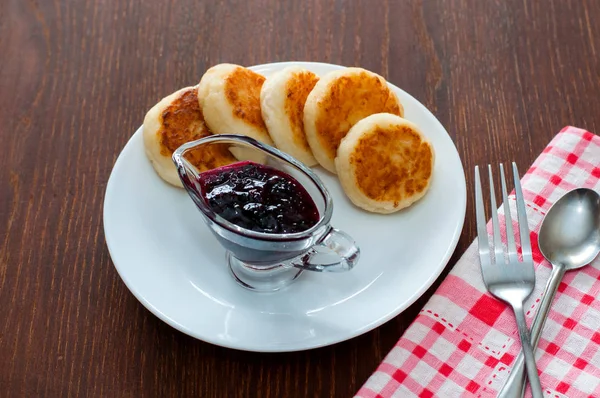 Reçelli peynirli krepler, çatal, çay kaşığı ve peçete ile beyaz bir tabakta, yatay formatta