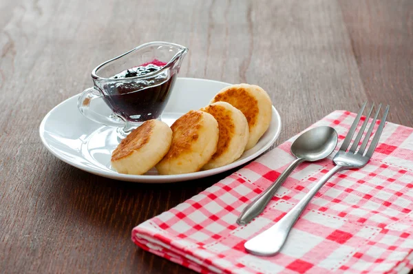 Reçelli peynirli krepler, çatal, çay kaşığı ve peçete ile beyaz bir tabakta, yatay formatta, yan görünüm