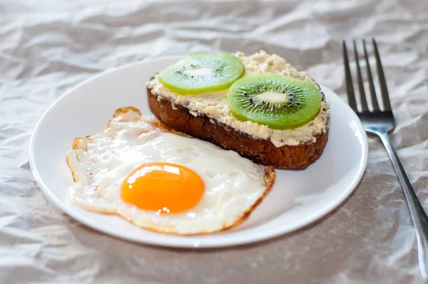 Délicieux et sain petit déjeuner. Œufs frits et sandwich kiwi sur assiette blanche — Photo