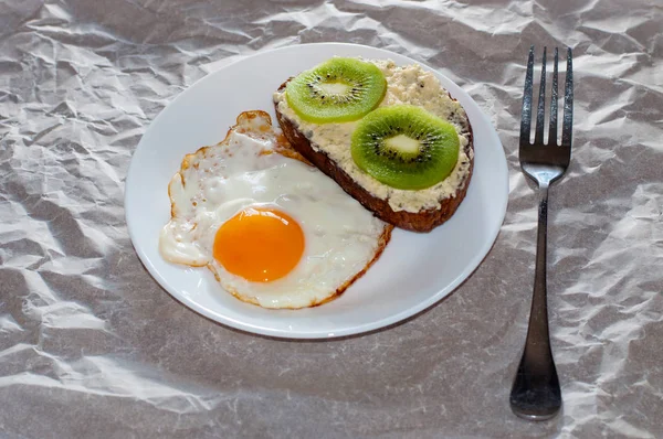 Вкусный и здоровый завтрак. Жареные яйца и сэндвич с киви на белой тарелке, крупный план, место для текста — стоковое фото