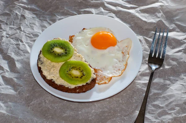 Вкусный и здоровый завтрак. Жареные яйца и сэндвич с киви на белой тарелке, крупный план, место для текста — стоковое фото