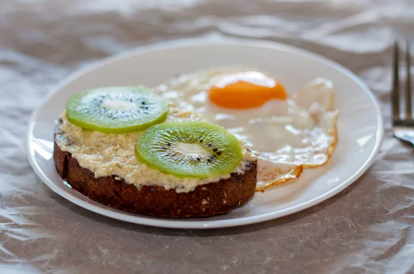 God och hälsosam frukost. Äggröra och Kiwi smörgås på en vit tallrik, närbild, uppifrån och sidovy — Stockfoto