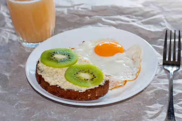 Petit déjeuner sain et savoureux, jus de fruits, sandwich complet avec kiwi et oeuf frit sur assiette blanche — Photo