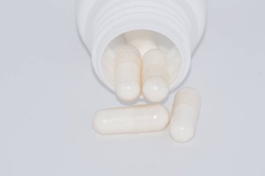 Beyaz arka plan üzerinde beyaz hap plastik bir kavanozdan düşmek.