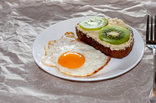 Výborná a zdravá snídaně. Smažená vejce a kiwi sendvič na bílém talíři, zblízka, místo pro text — Stock fotografie