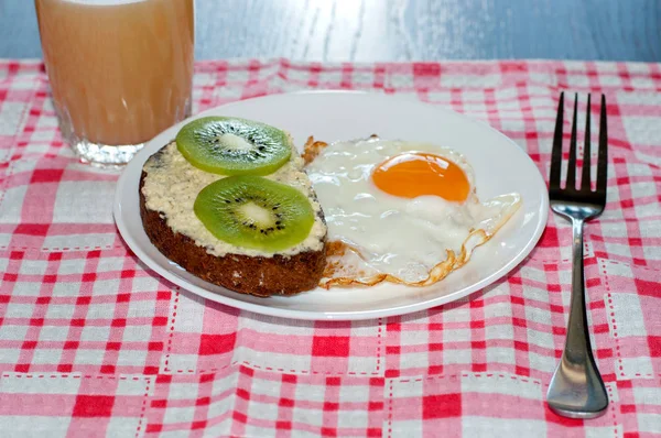 Zdrowe i smaczne śniadanie, sok z pigwy, pieczywo pełnoziarniste z kiwi i smażonym jajkiem na białej płytce — Zdjęcie stockowe