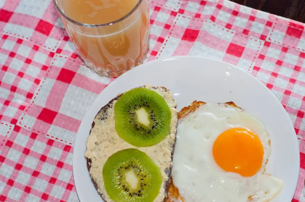 Gesundes, schmackhaftes Frühstück, Quittensaft, Kiwi-Vollkornsandwich und Spiegelei auf weißem Teller — Stockfoto