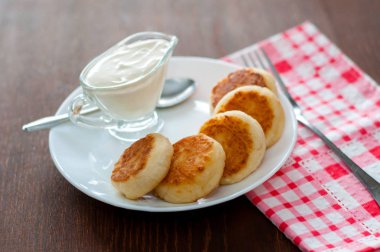 Üstten beyaz bir tabak görünümünde ekşi krema ile kızarmış peynir krep. Menü tasarımı için kullanılabilir.