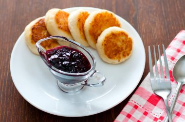 Kuş üzümü reçeli ile Peynir krep, bir çatal, bir çay kaşığı ve peçete ile beyaz bir tabak üzerinde, üstten görünümü.