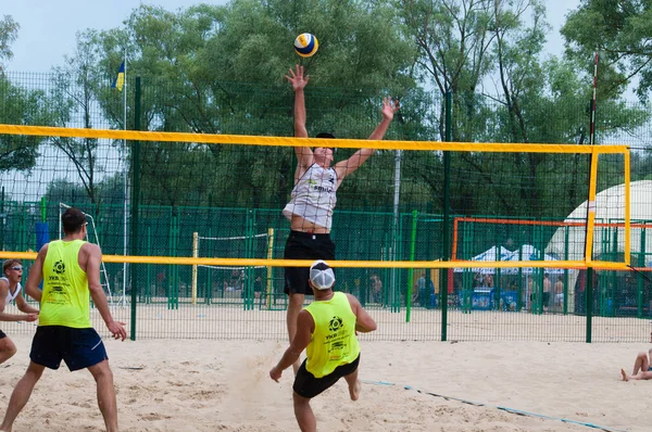 Ukraine, Chernigov, June 9, 2019: Beach Volleyball Championship of the city. Beautiful young sports strong men play volleyball on the city beach, in the summer, in sunny hot weather. — Stock Photo, Image