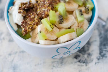 Granola, kivi, muz ve kase yunan yoğurt, gri beton arka plan üzerinde bir tabak, üstten yakından görünümü. Kilo kaybı ve uygun beslenme için Fitness diyet