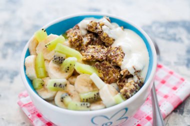 Granola, kivi, muz ve Yunan yoğurt gri beton arka plan üzerinde bir kase içinde, kırmızı bir peçete üzerinde, üstten alan görünümü kopyalayın. Kilo kaybı, doğru beslenme ve sağlıklı bir yaşam tarzı için Fitness diyet