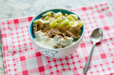 Granola yunan yoğurt kivi ve muz pembe bir peçete, yukarıdan yakından görünümü üzerinde kase içinde. Kilo kaybı, uygun ve lezzetli gıda için Fitness diyet