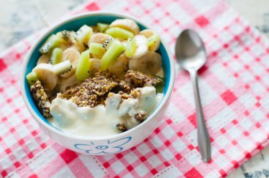 Granola yunan yoğurt kivi ve muz pembe bir peçete, yukarıdan yakından görünümü üzerinde kase içinde. Kilo kaybı, uygun ve lezzetli gıda için Fitness diyet