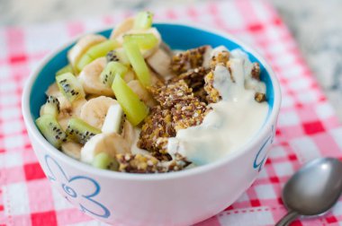 Granola Yunan yoğurt kivi ve muz ile kase de pembe bir peçete üzerinde bir kaşık, üstten görünümü. Kilo kaybı, uygun ve lezzetli gıda için Fitness diyet