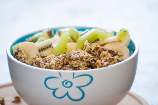 Healthy breakfast of granola, kiwi, banana and yogurt in a bowl on a wooden tray. Fitness diet for weight loss — Stock Photo, Image