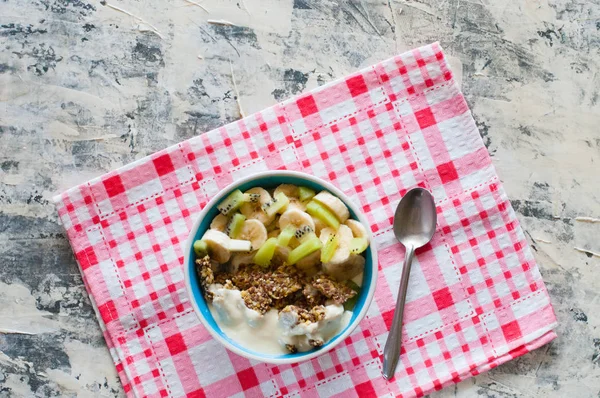 Granola with Greek yogurt kiwi and banana in bowl with a spoon on a pink napkin, view from the top, flat lay. Fitness diet for weight loss, proper and tasty food — Stock Photo, Image