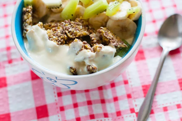 Granola with Greek yogurt kiwi and banana in bowl on a pink napkin, close-up view from the top. Fitness diet for weight loss, proper and tasty food — Stock Photo, Image