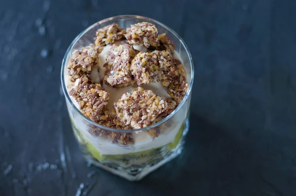 Yaourt grec, granola, banane et kiwi. Dessert en bécher de verre sur fond sombre, macro gros plan. Concept corps et alimentation saine — Photo