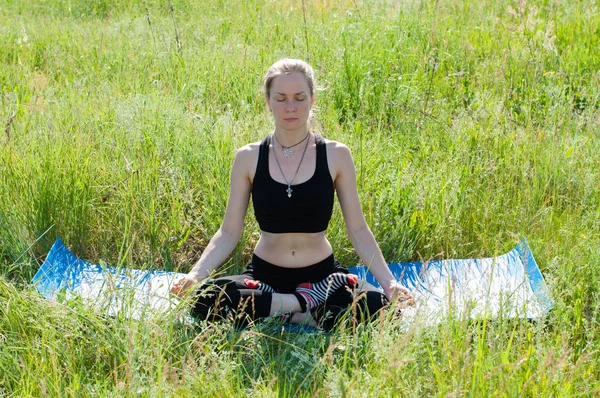 Jovem mulher bonita em traje de treino faz ioga sobre a natureza no verão, medita — Fotografia de Stock