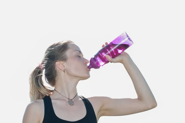 Joven hermosa mujer muy bonita en un traje deportivo bebe agua de una botella después del entrenamiento en yoga, gimnasia al aire libre en el verano — Foto de Stock